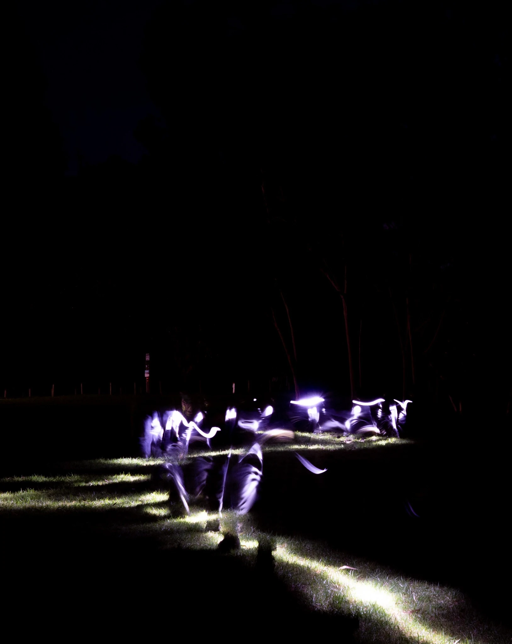 Wide ghost-like figures on a path at night