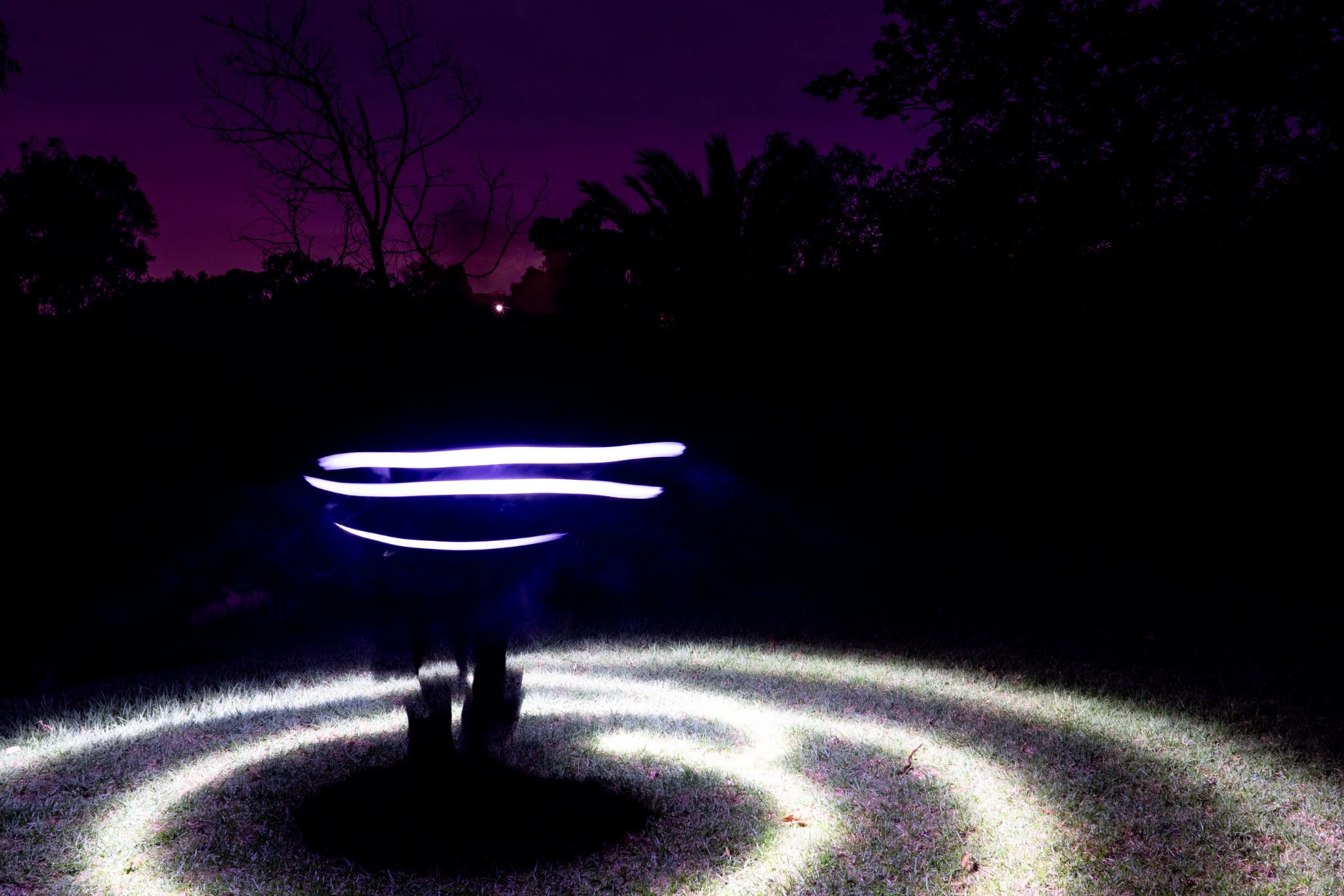 Purple light trail extending across a dark field